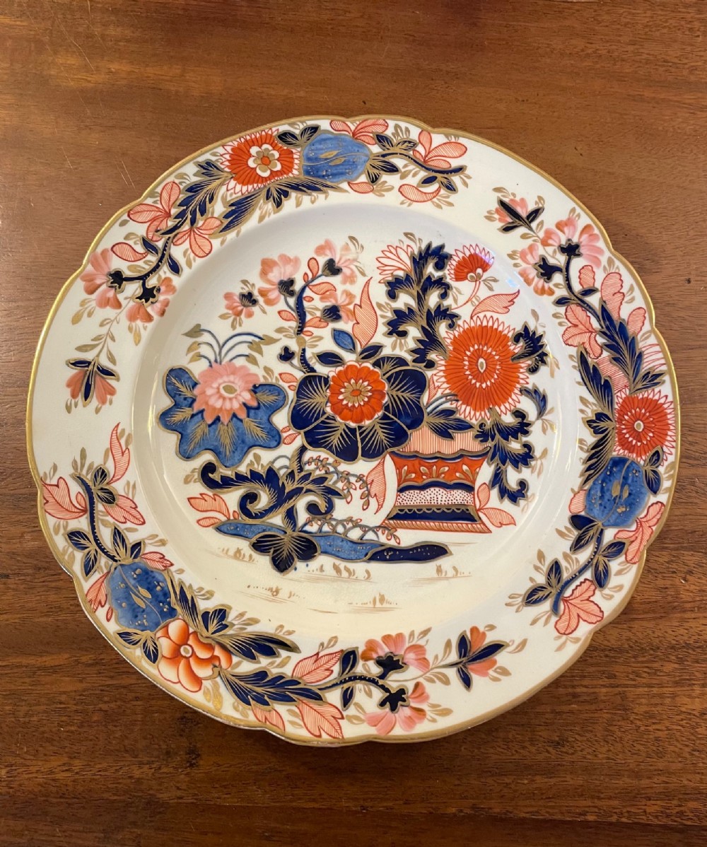 A set of three circular early nineteenth-century ceramic plates featuring hand-painted floral urn motifs in cobalt blue, iron red, and gold with scalloped edges. View II