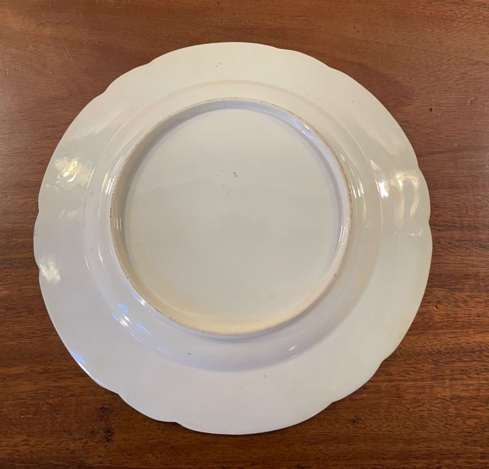A set of three circular early nineteenth-century ceramic plates featuring hand-painted floral urn motifs in cobalt blue, iron red, and gold with scalloped edges. View V