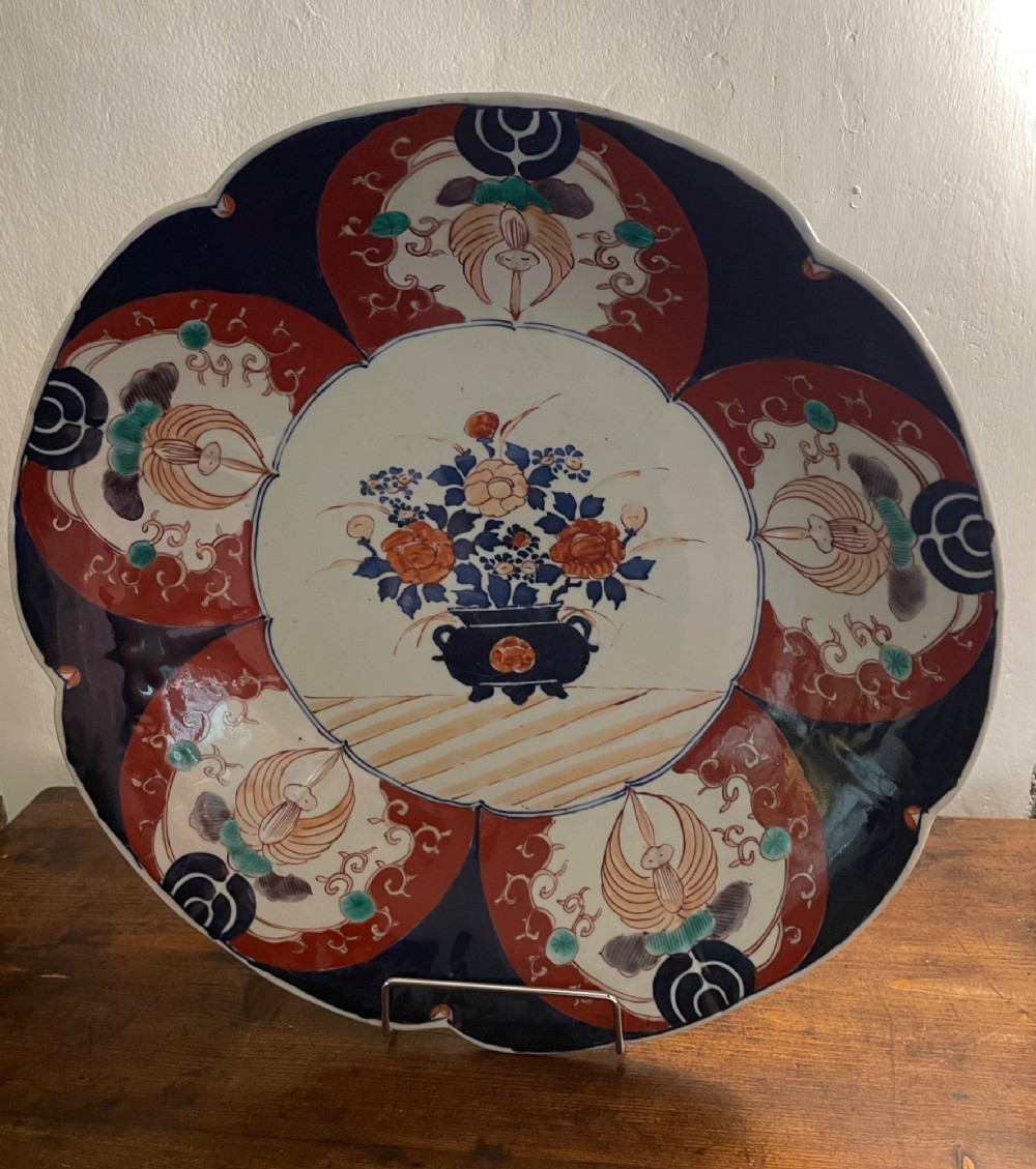 A large late 19th-century Japanese Imari porcelain charger decorated in cobalt blue, iron-red, and gold, with a central vase of flowers surrounded by radiating lobed panels. View II