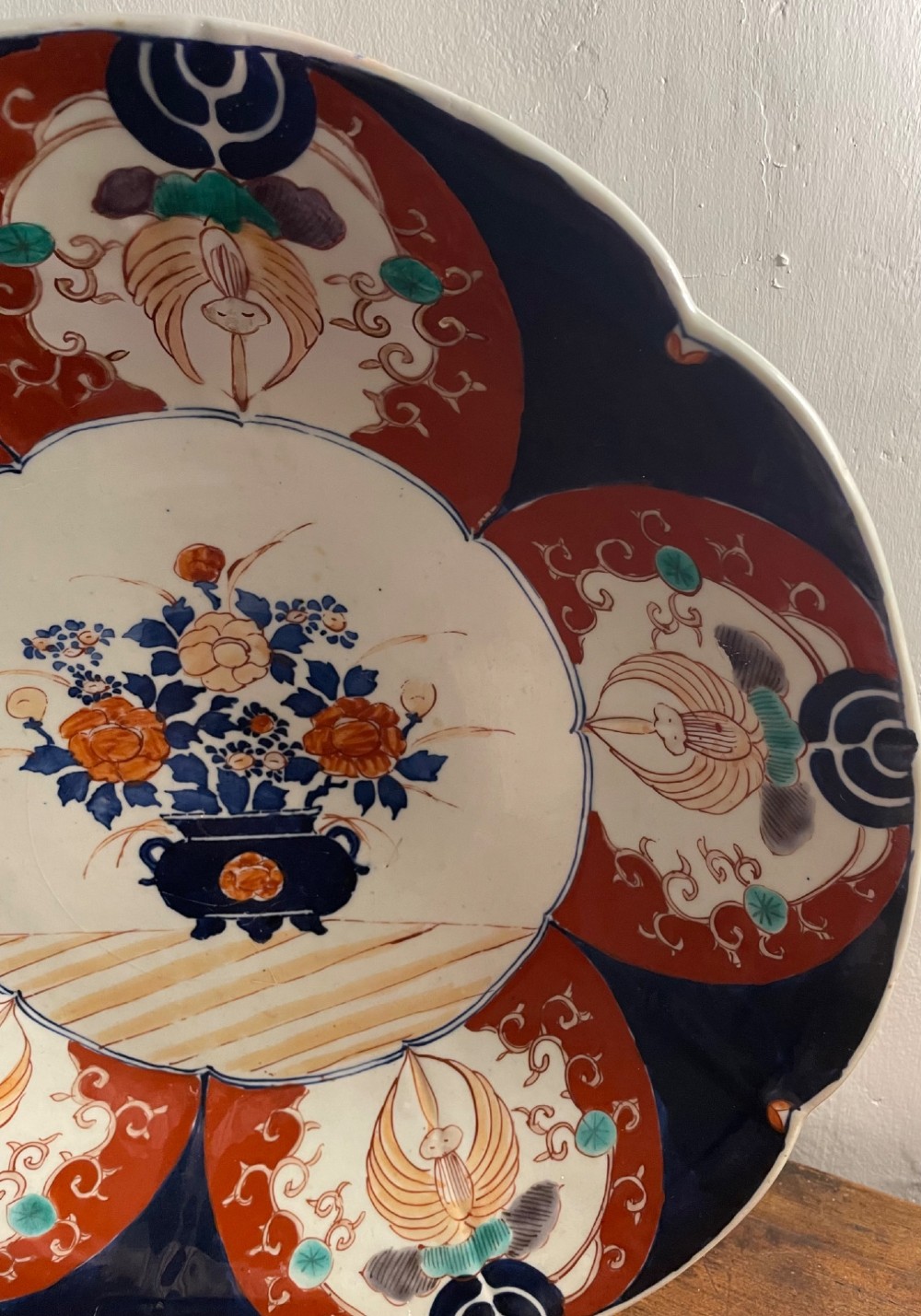 A large late 19th-century Japanese Imari porcelain charger decorated in cobalt blue, iron-red, and gold, with a central vase of flowers surrounded by radiating lobed panels. View V