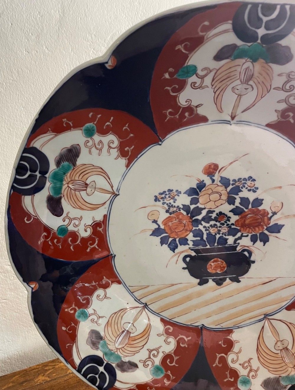 A large late 19th-century Japanese Imari porcelain charger decorated in cobalt blue, iron-red, and gold, with a central vase of flowers surrounded by radiating lobed panels. View VI