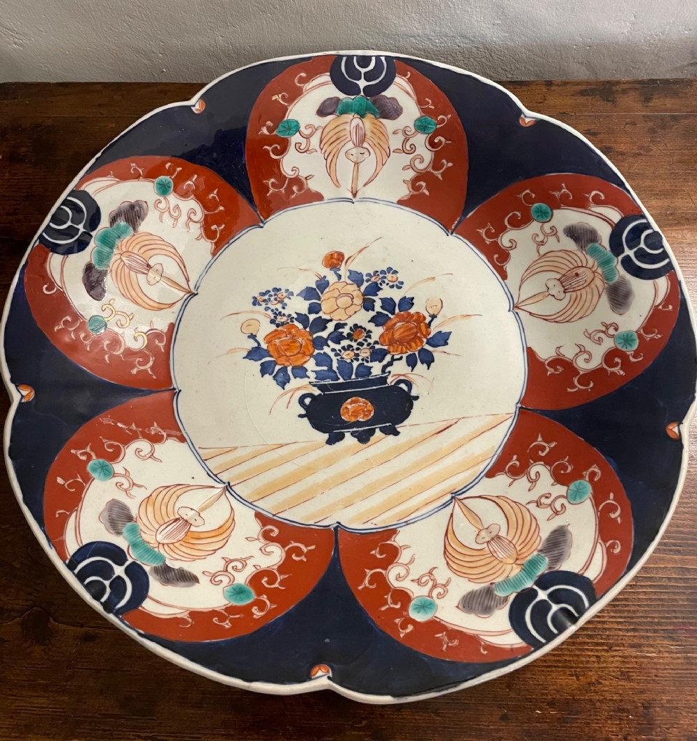 A large late 19th-century Japanese Imari porcelain charger decorated in cobalt blue, iron-red, and gold, with a central vase of flowers surrounded by radiating lobed panels. View VII
