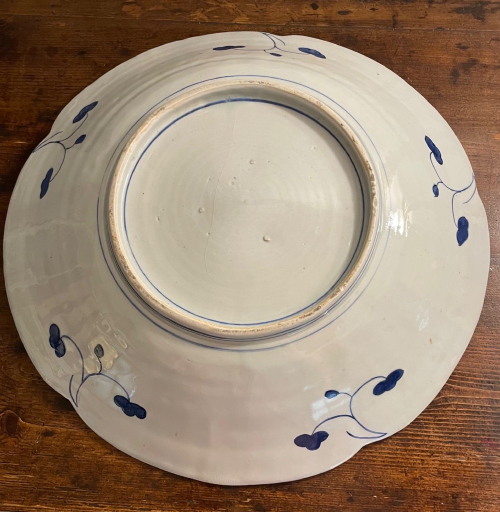 A large late 19th-century Japanese Imari porcelain charger decorated in cobalt blue, iron-red, and gold, with a central vase of flowers surrounded by radiating lobed panels. View VIII