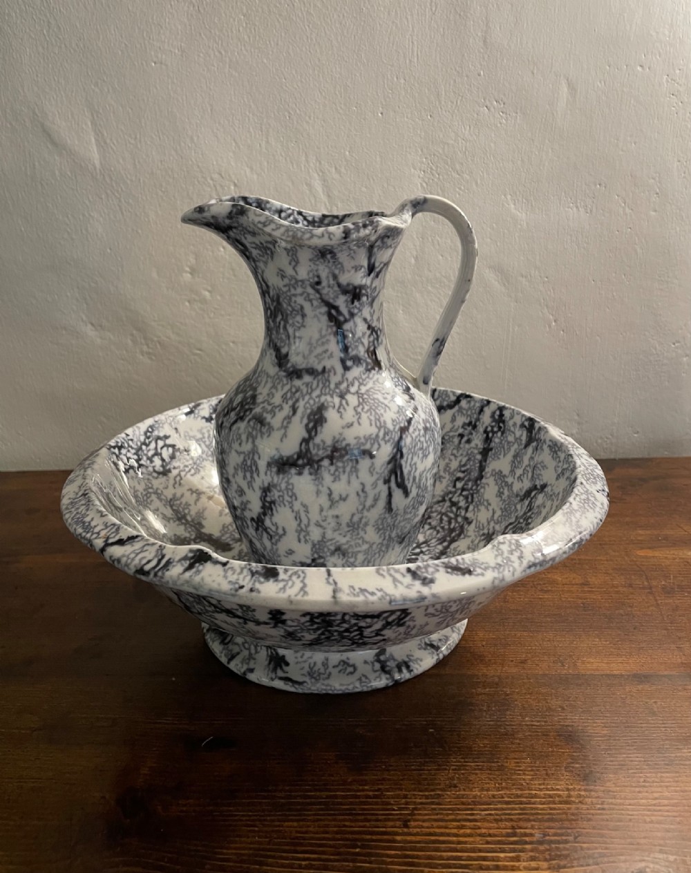 An early nineteenth-century Staffordshire flow blue ceramic wash set comprising a flared jug and matching wide wash basin with a mottled blue pattern. View X