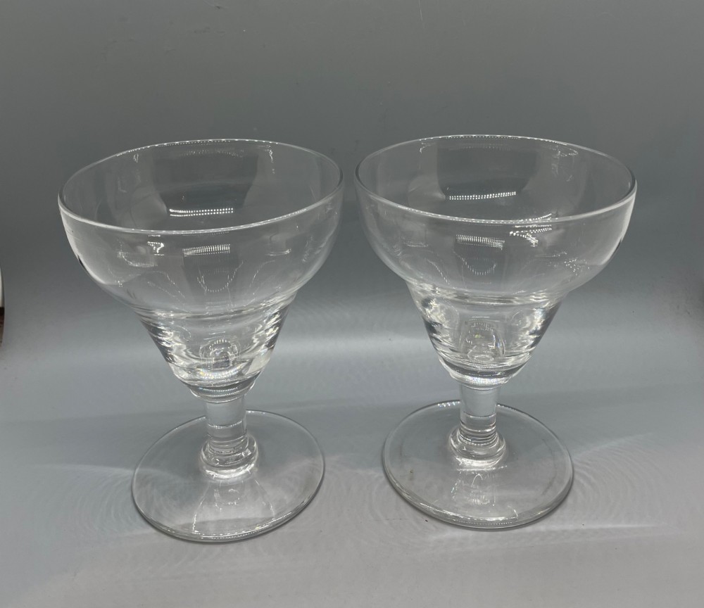 A matched pair of clear Georgian glass rummers featuring ogee-shaped bowls, short stems, and circular flat feet.