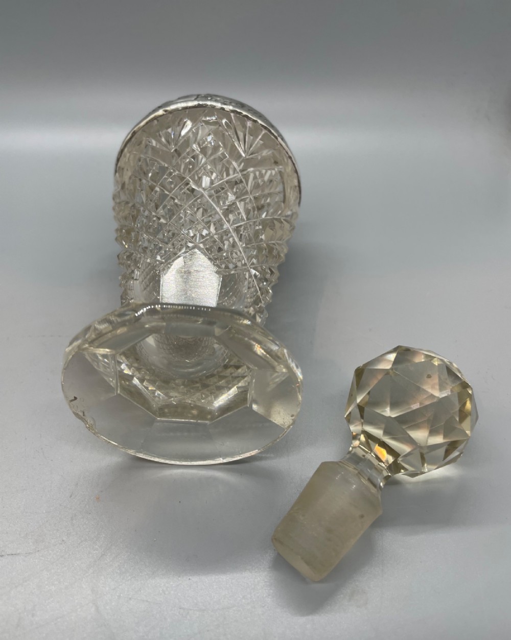 A pair of George V cut glass scent bottles featuring embossed sterling silver mounts and faceted glass stoppers. View VII