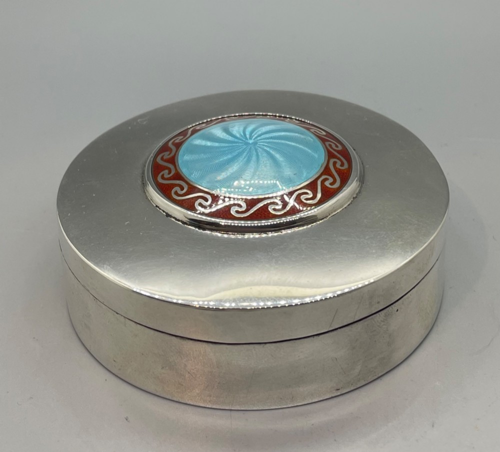 A circular sterling silver trinket box featuring a central light blue guilloche enamel medallion encircled by a red enamel border. View II
