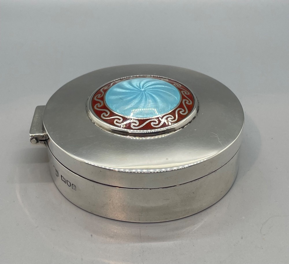 A circular sterling silver trinket box featuring a central light blue guilloche enamel medallion encircled by a red enamel border. View IV