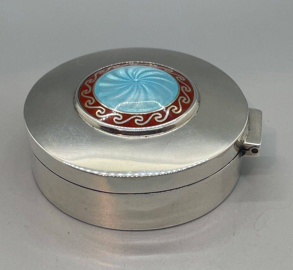 A circular sterling silver trinket box featuring a central light blue guilloche enamel medallion encircled by a red enamel border. View VI
