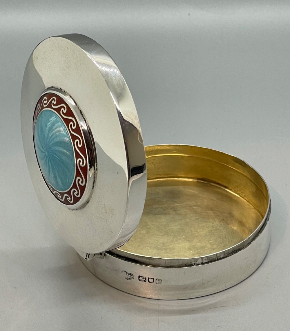 A circular sterling silver trinket box featuring a central light blue guilloche enamel medallion encircled by a red enamel border. View IX