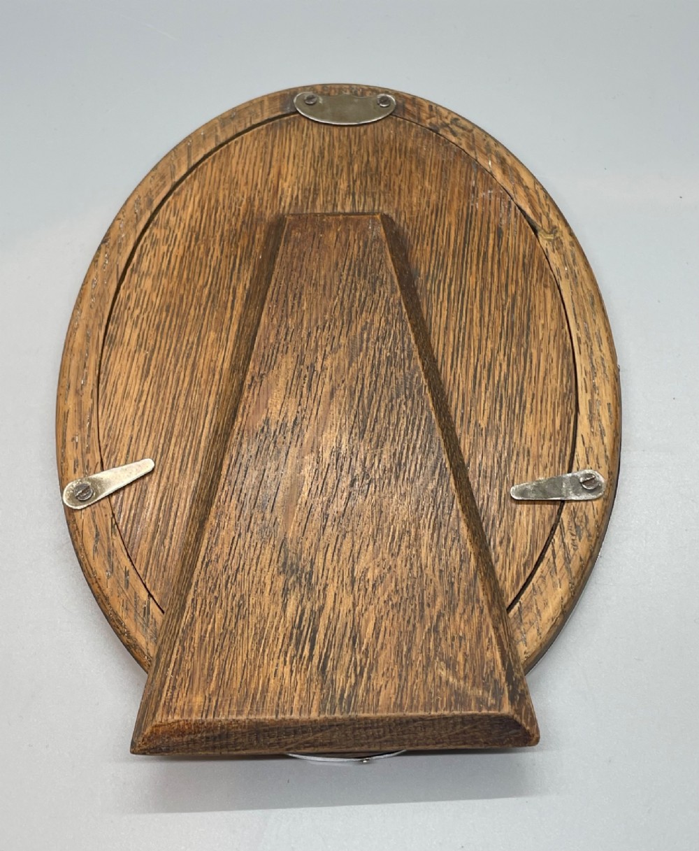 A George V oval sterling silver photo frame featuring a plain polished silver border and a dark wood easel backing. View VII
