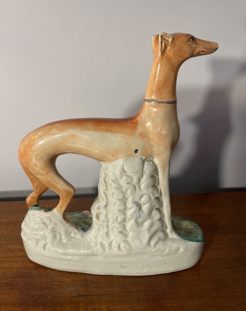 An antique Staffordshire earthenware figure depicting a standing tan hound with a crouching hare on a green and blue glazed base. View III