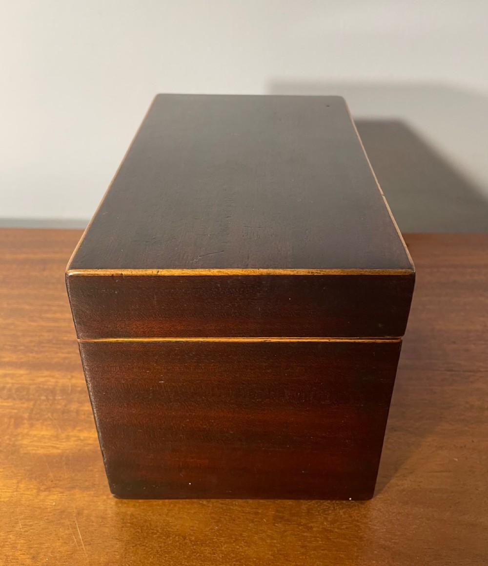 A rectangular Georgian dark mahogany tea caddy featuring delicate boxwood edge stringing and a diamond-shaped bone escutcheon on the front panel. View II