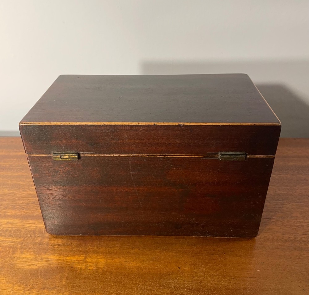 A rectangular Georgian dark mahogany tea caddy featuring delicate boxwood edge stringing and a diamond-shaped bone escutcheon on the front panel. View III