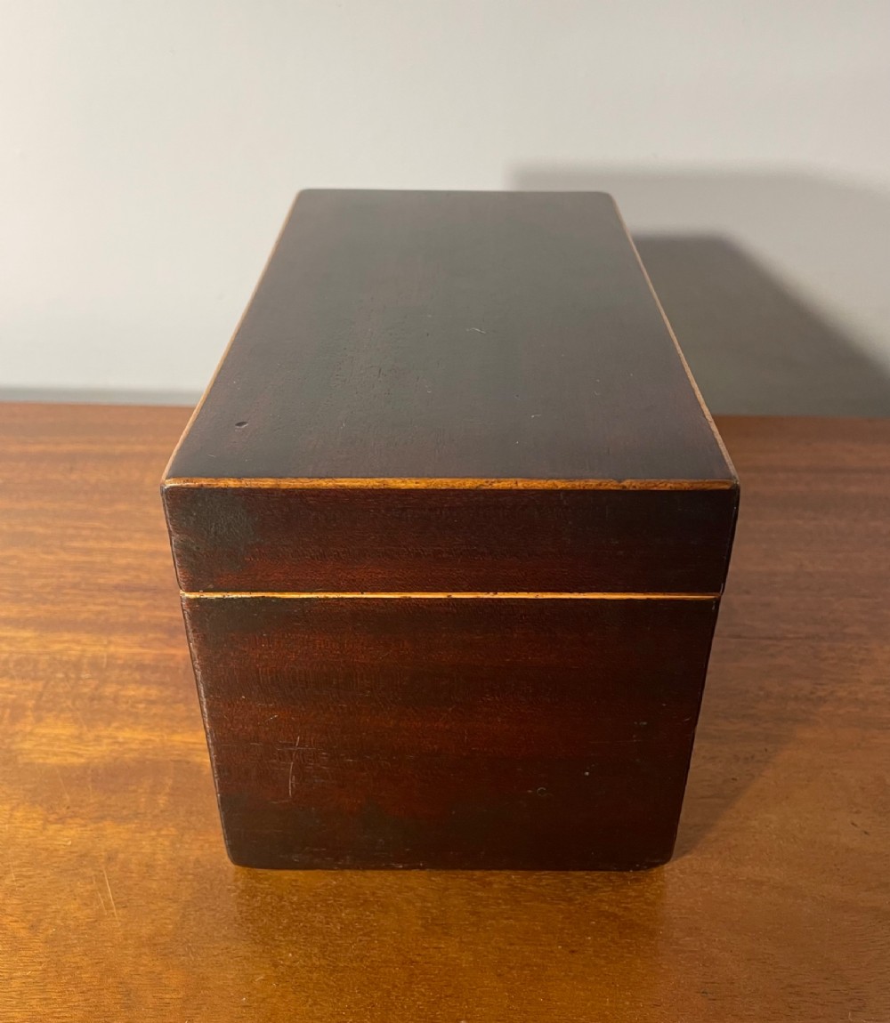 A rectangular Georgian dark mahogany tea caddy featuring delicate boxwood edge stringing and a diamond-shaped bone escutcheon on the front panel. View IV