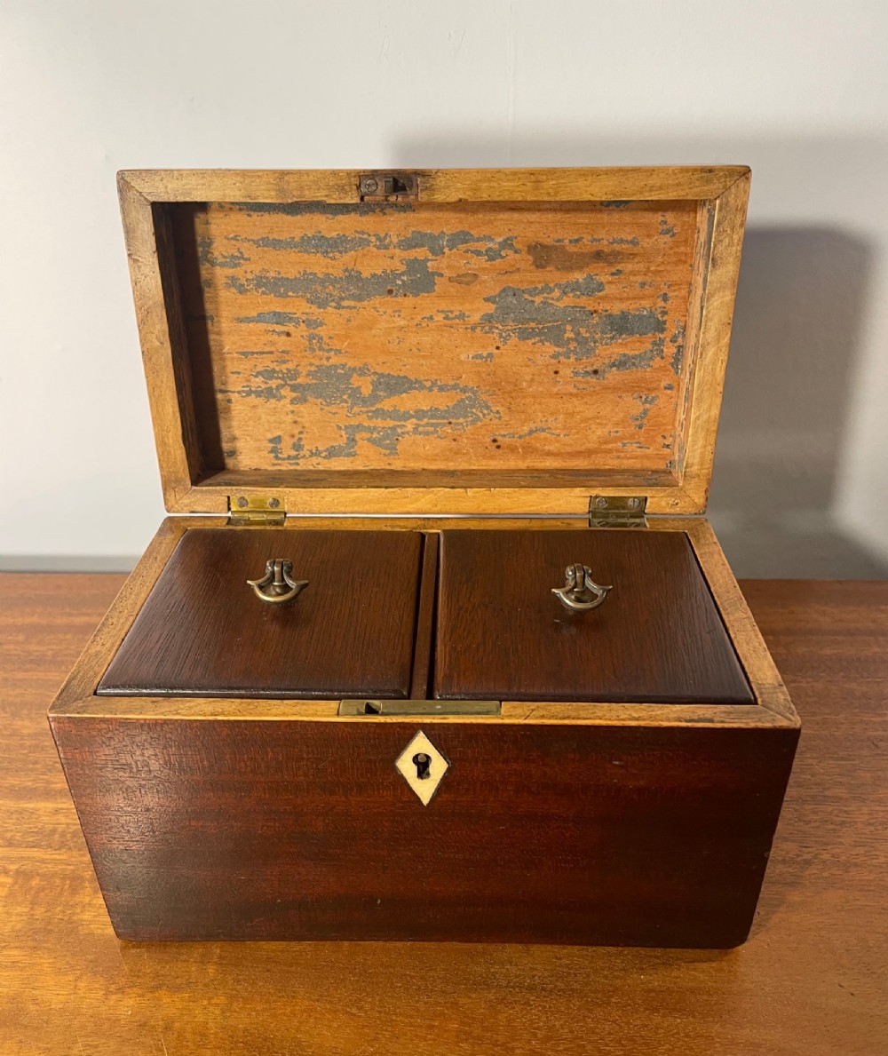 A rectangular Georgian dark mahogany tea caddy featuring delicate boxwood edge stringing and a diamond-shaped bone escutcheon on the front panel. View V