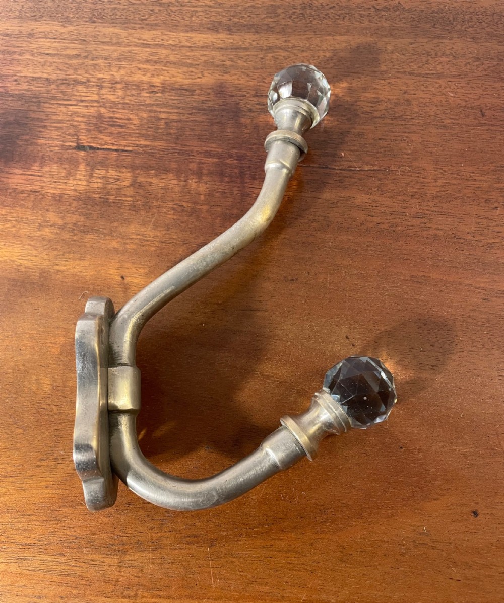 A set of three antique French brass coat hooks featuring faceted clear glass finials on curved double arms. View V