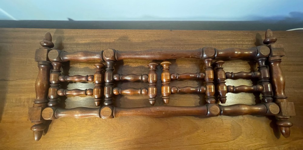 An Edwardian turned mahogany wall-mounted coat rack featuring horizontal spindle rails, four turned pegs, and decorative finials. View III
