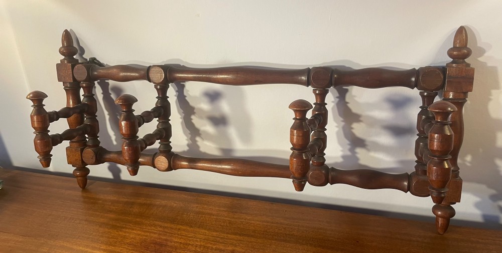 An Edwardian turned mahogany wall-mounted coat rack featuring horizontal spindle rails, four turned pegs, and decorative finials. View IV