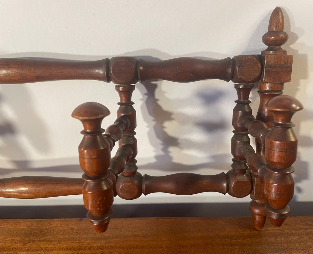 An Edwardian turned mahogany wall-mounted coat rack featuring horizontal spindle rails, four turned pegs, and decorative finials. View VI
