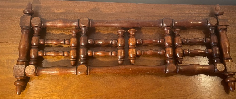 An Edwardian turned mahogany wall-mounted coat rack featuring horizontal spindle rails, four turned pegs, and decorative finials. View X