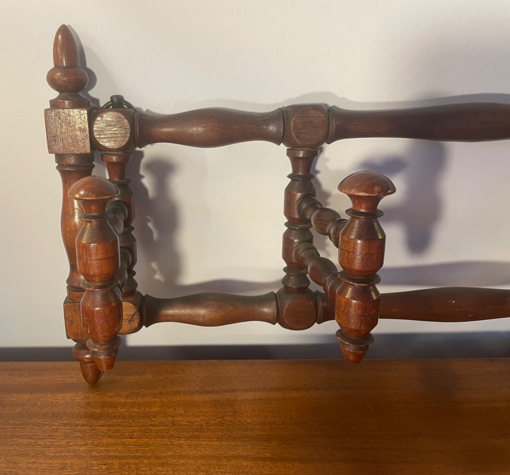 An Edwardian turned mahogany wall-mounted coat rack featuring horizontal spindle rails, four turned pegs, and decorative finials. View XI
