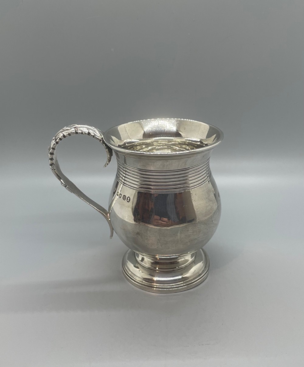 A George IV sterling silver baluster mug featuring a reeded collar, decorative acanthus leaf handle, and a stepped circular pedestal base. View III