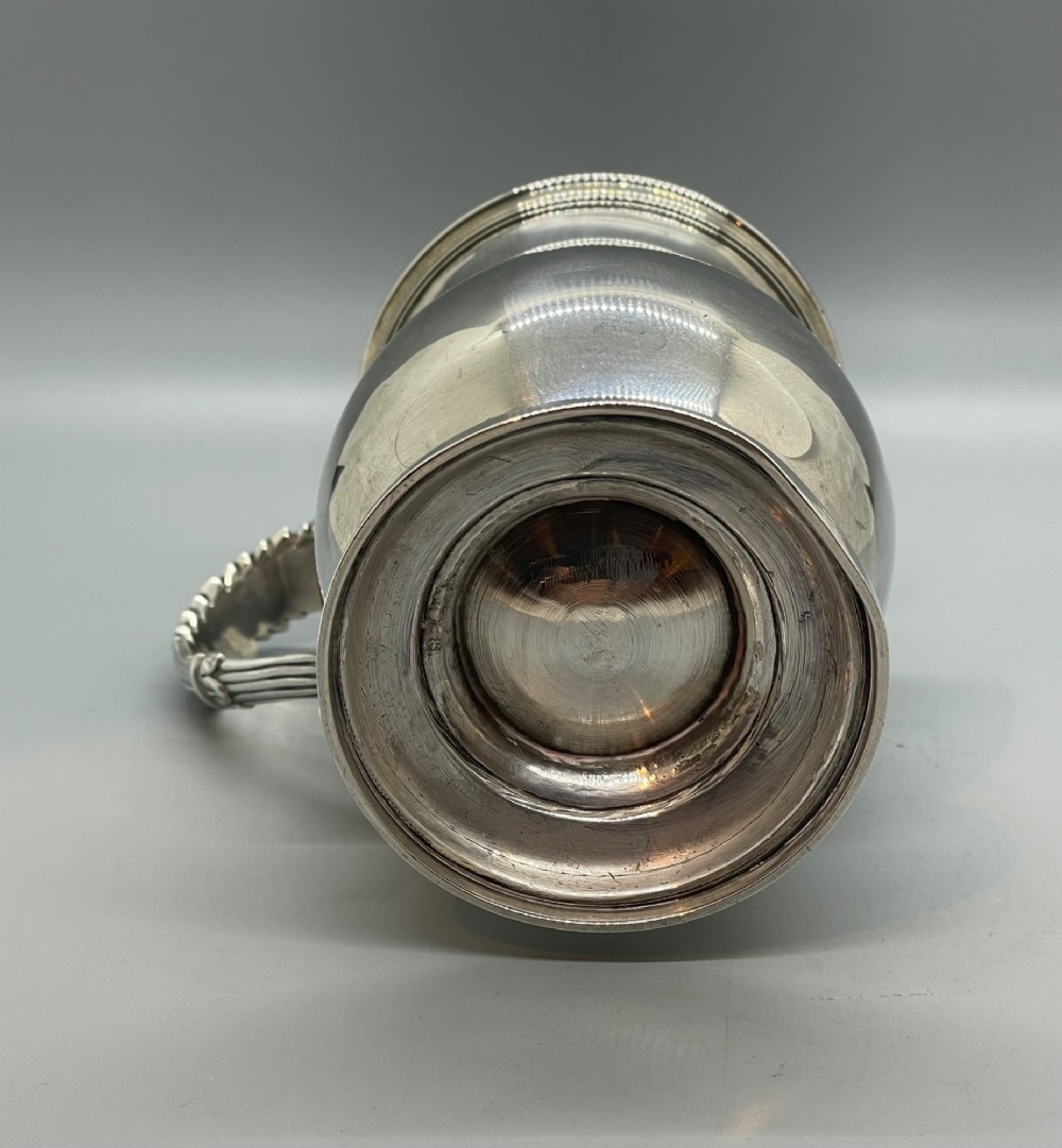 A George IV sterling silver baluster mug featuring a reeded collar, decorative acanthus leaf handle, and a stepped circular pedestal base. View VIII