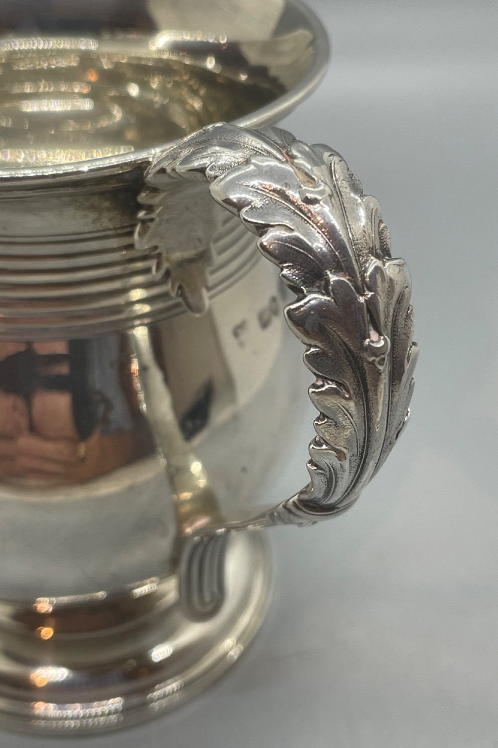 A George IV sterling silver baluster mug featuring a reeded collar, decorative acanthus leaf handle, and a stepped circular pedestal base. View IX
