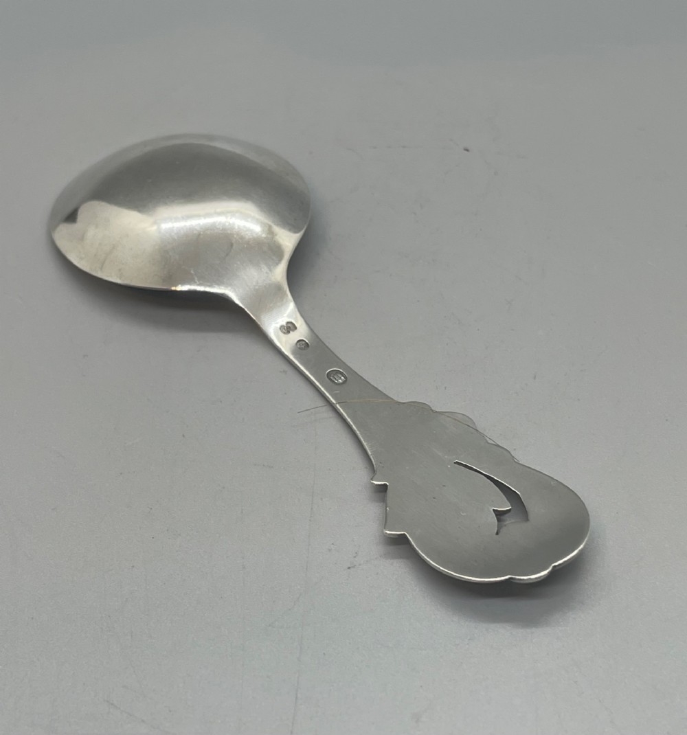 A vintage solid silver caddy spoon featuring a rounded bowl and an ornate leaf and scroll decorated handle. View II