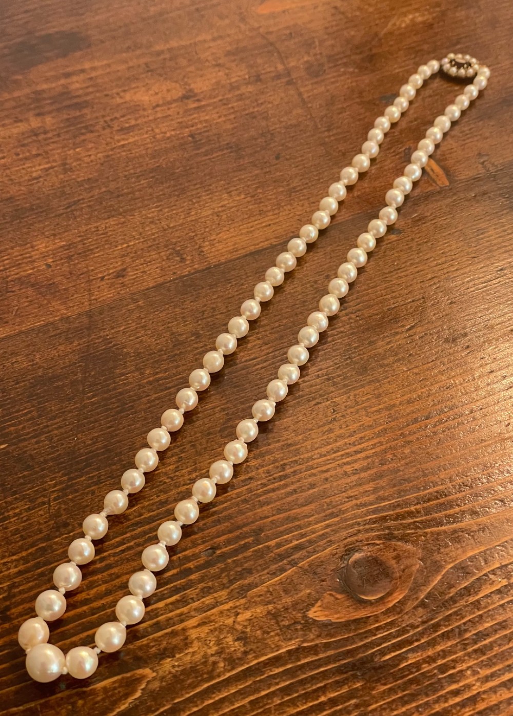 A strand of cream cultured pearls featuring a central oval red garnet clasp set in gold. View VI