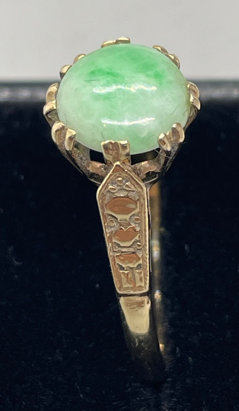 A vintage 9ct yellow gold ring featuring a polished round green jade cabochon in a multi-claw setting with geometric engraved shoulders. View III