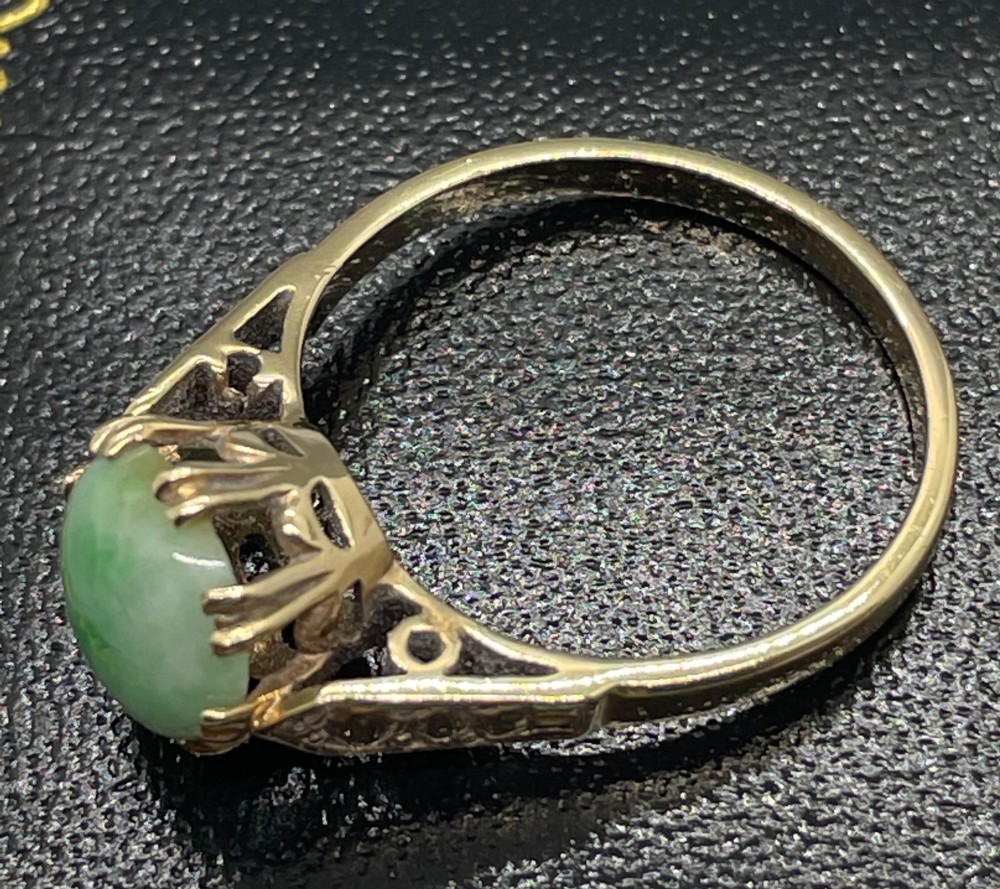 A vintage 9ct yellow gold ring featuring a polished round green jade cabochon in a multi-claw setting with geometric engraved shoulders. View VI