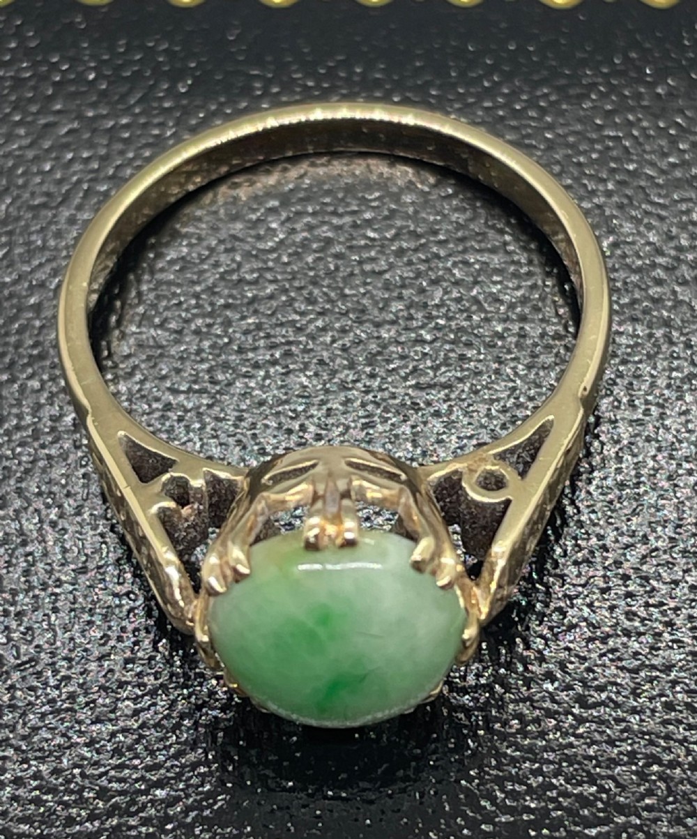 A vintage 9ct yellow gold ring featuring a polished round green jade cabochon in a multi-claw setting with geometric engraved shoulders. View VII