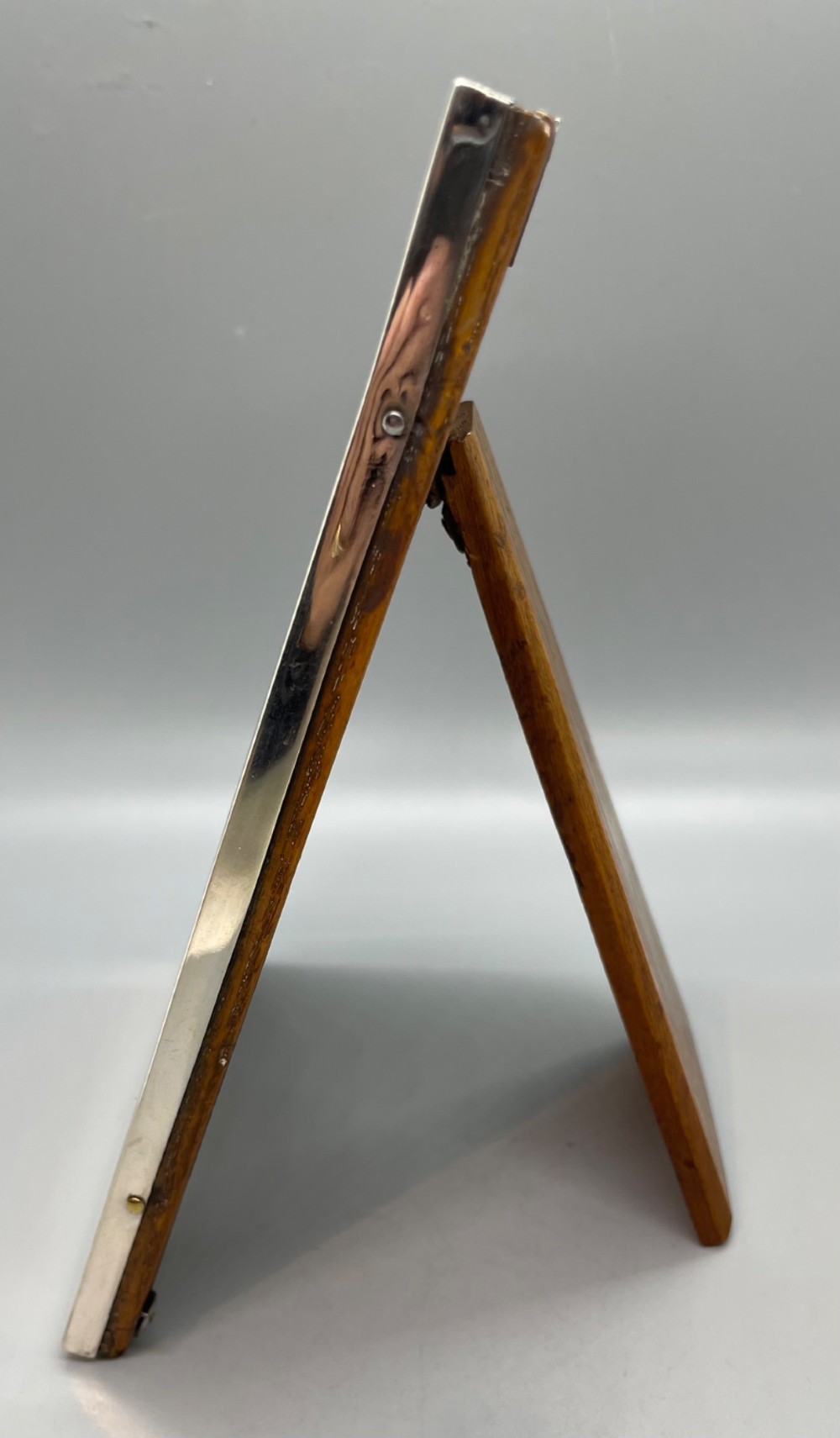 An upright rectangular sterling silver photo frame with a polished border, easel back stand, and burgundy fabric interior. View IV