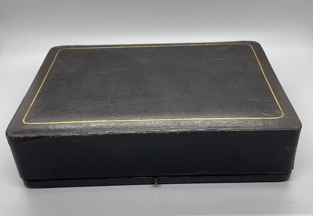 A set of six circular Edwardian sterling silver napkin rings with engraved patterns, displayed inside an open presentation box with green velvet lining. View XIV