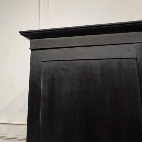 An ebonised black timber linen cupboard featuring two upper panelled doors above two short and two long drawers with brass drop handles. View II