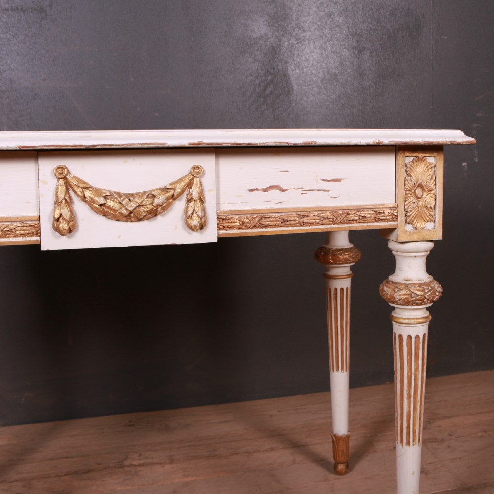 A Gustavian off-white painted writing table with gilded drapery swags, carved rosette blocks, and fluted legs. View II