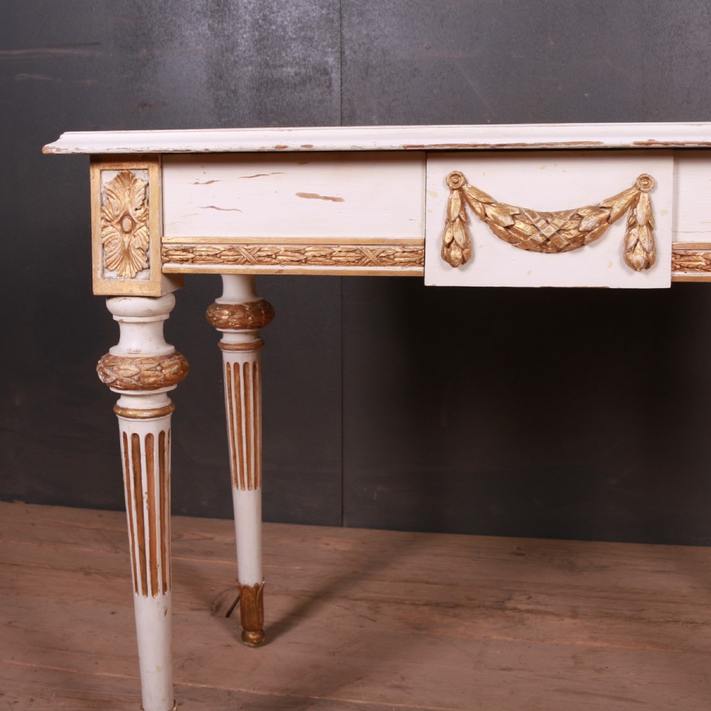 A Gustavian off-white painted writing table with gilded drapery swags, carved rosette blocks, and fluted legs. View III