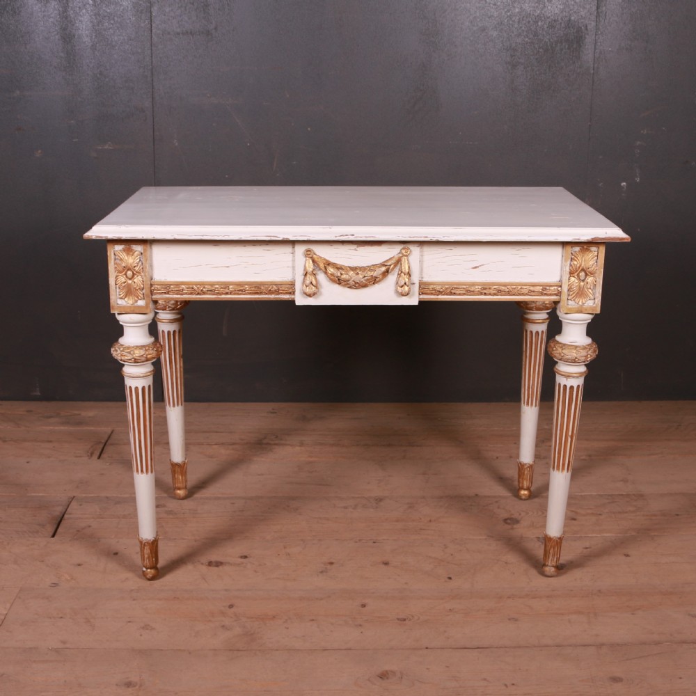 A Gustavian off-white painted writing table with gilded drapery swags, carved rosette blocks, and fluted legs. View VII