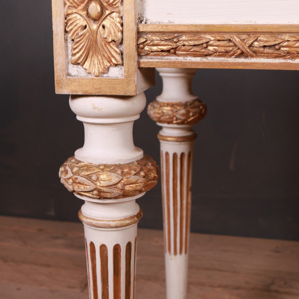 A Gustavian off-white painted writing table with gilded drapery swags, carved rosette blocks, and fluted legs. View VIII