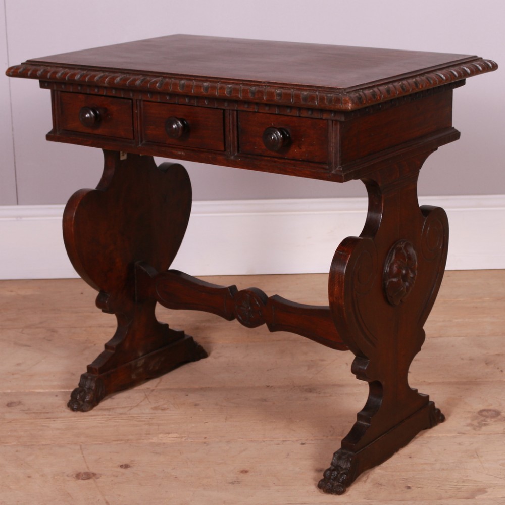 A dark walnut side table featuring three frieze drawers, carved gadrooned edges, scroll-shaped trestle legs, and a carved central stretcher.