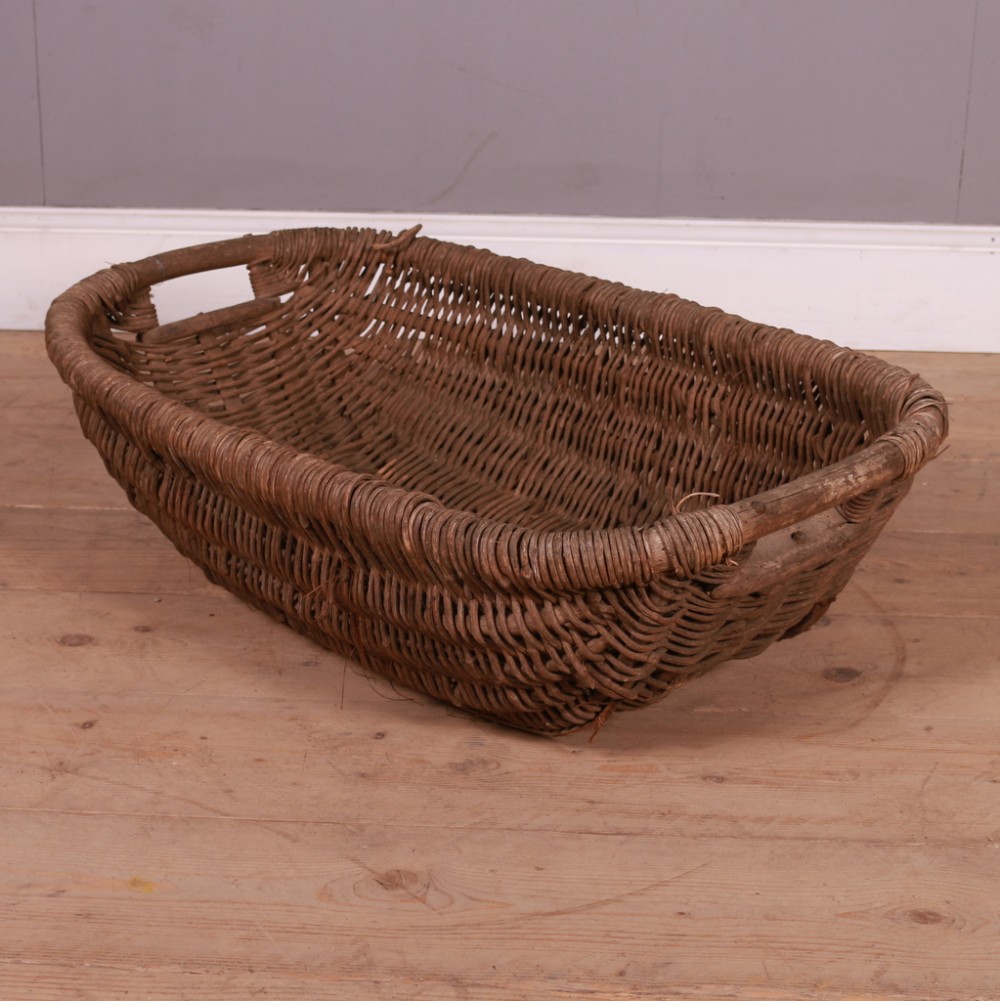 A large, rectangular French woven wicker grape basket with thick wooden carry handles and a weathered brown finish.