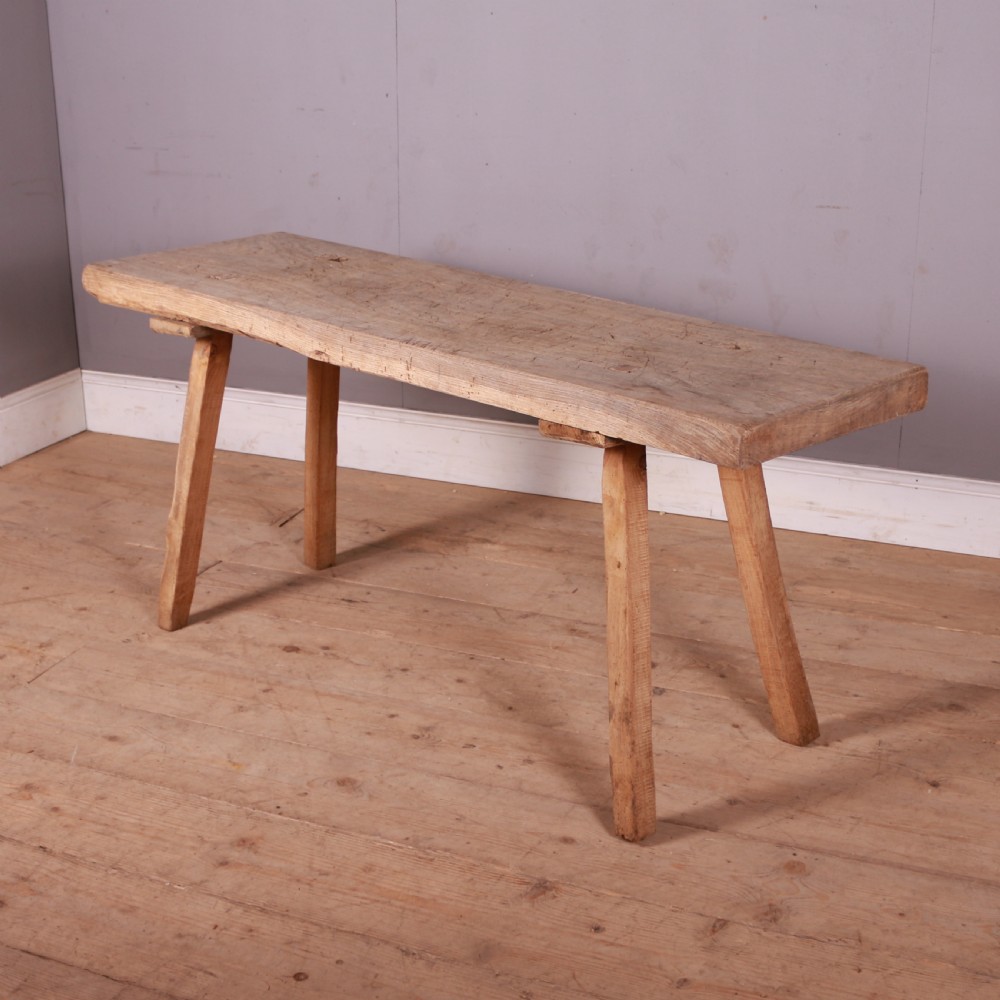 A long, narrow rustic French trestle table constructed from scrubbed sycamore and elm with four splayed legs.