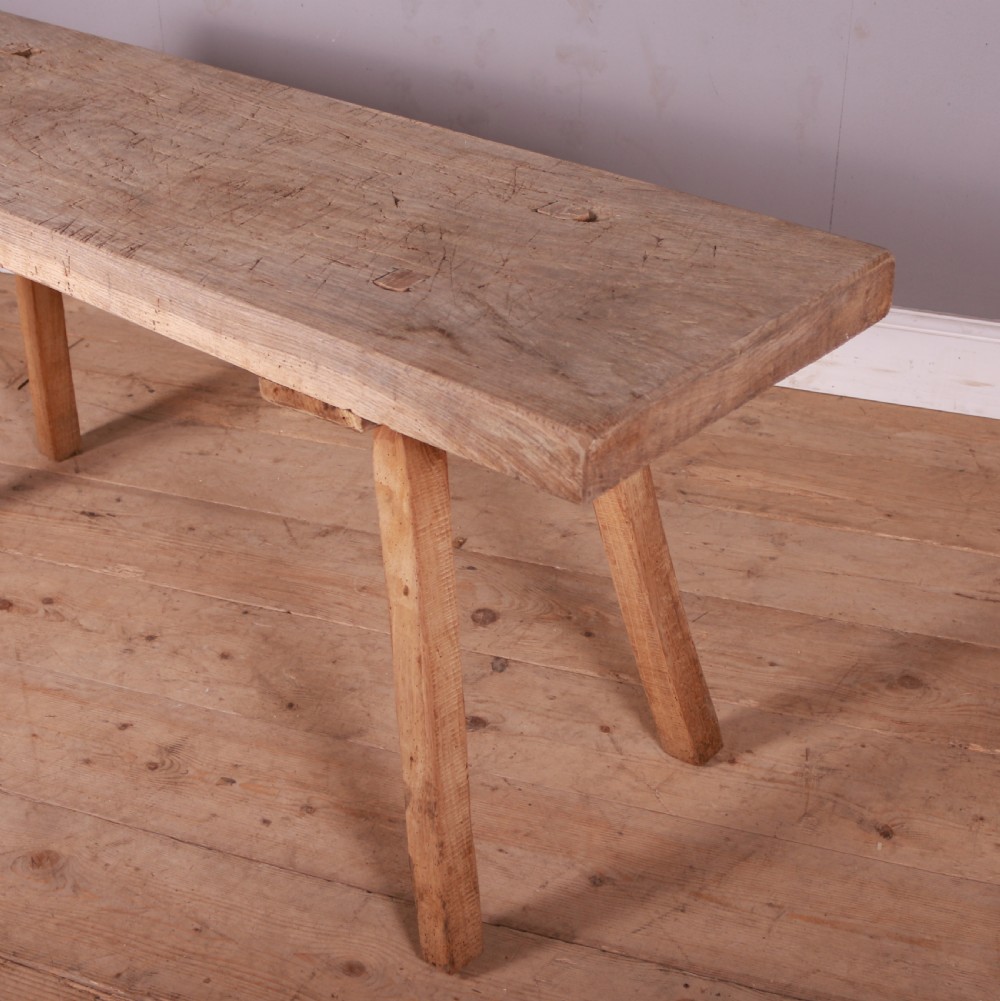 A long, narrow rustic French trestle table constructed from scrubbed sycamore and elm with four splayed legs. View II