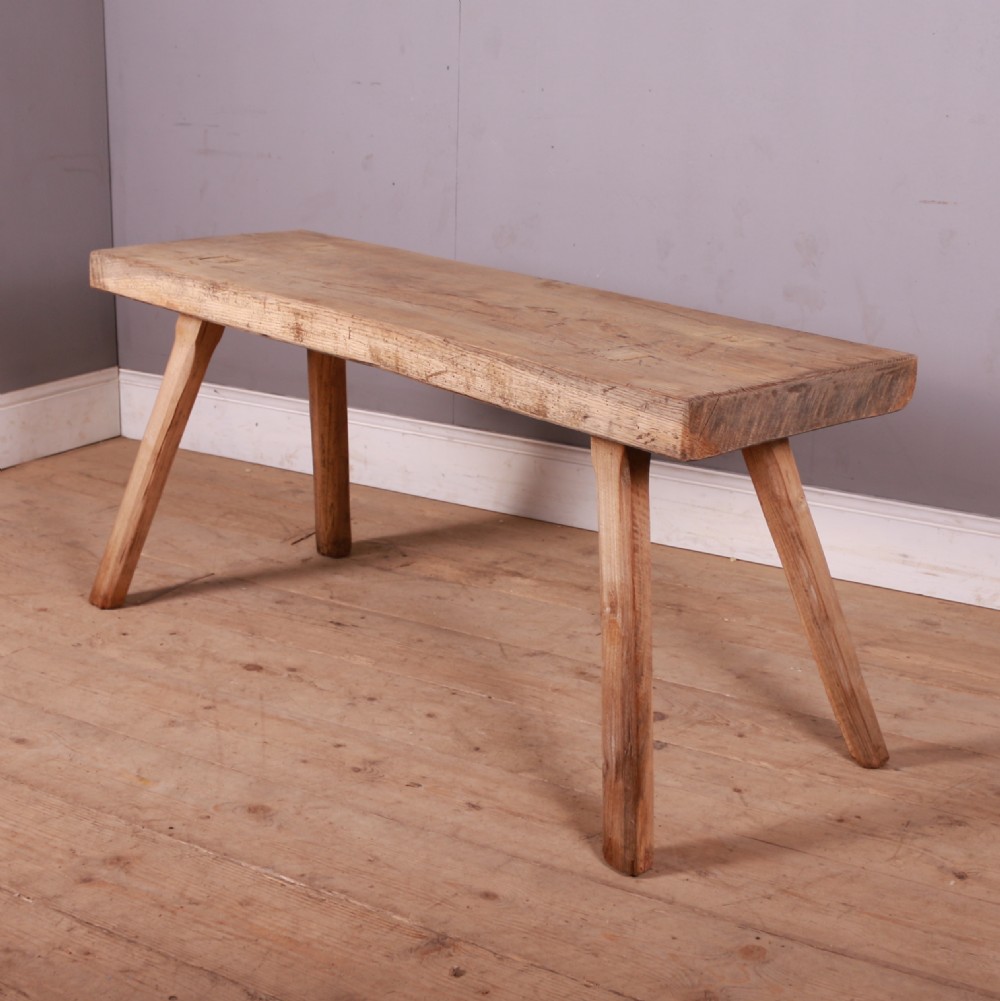 A rectangular wooden trestle table crafted from pale scrubbed timber with four angled splayed legs.
