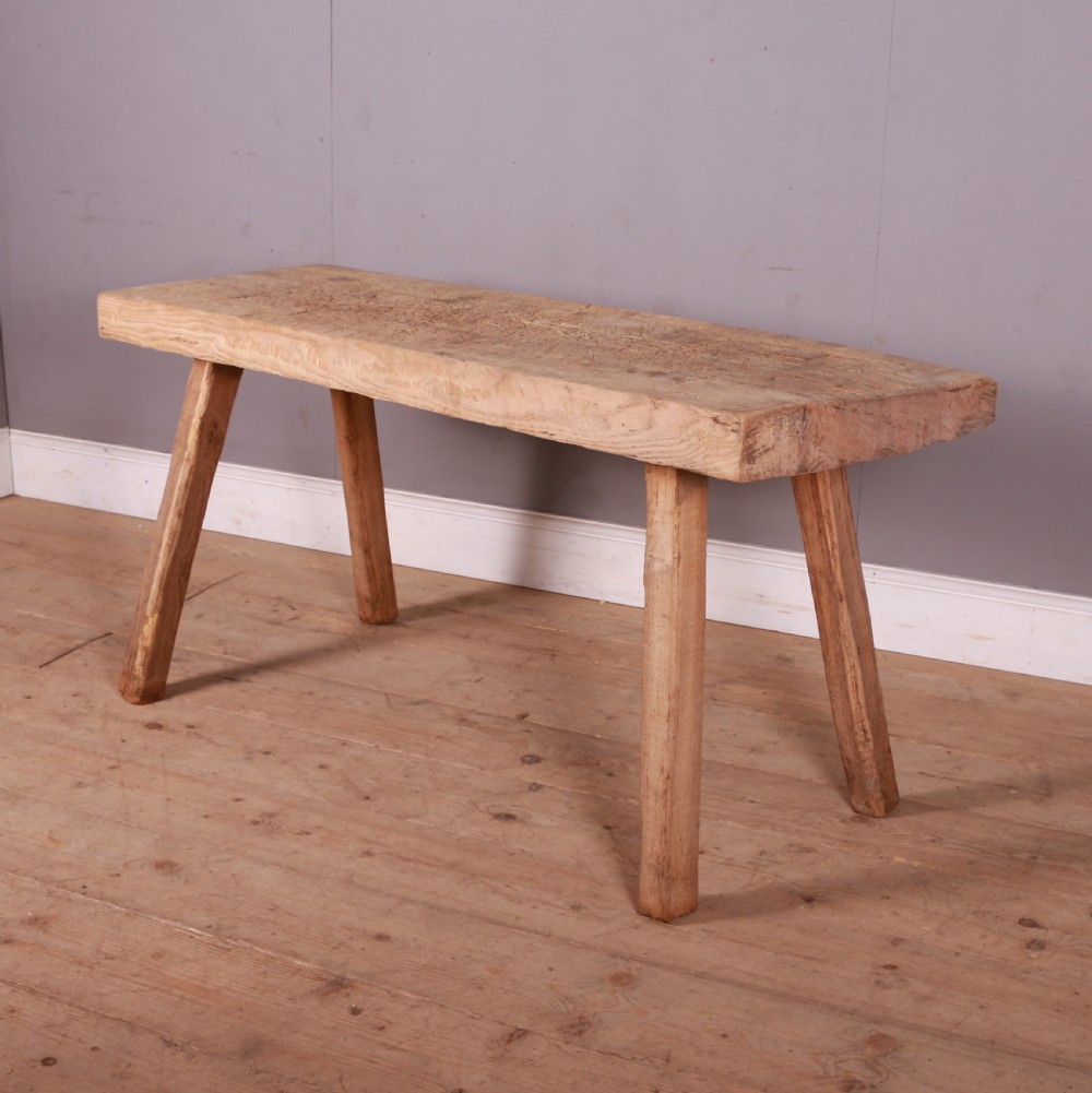 A rustic scrubbed sycamore and elm trestle table with a thick rectangular top and four splayed wooden legs.