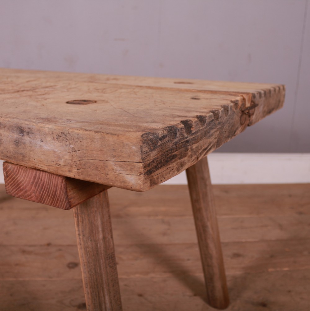 A rustic French scrubbed sycamore and elm trestle table featuring a thick plank top with visible peg construction and splayed wooden legs. View III