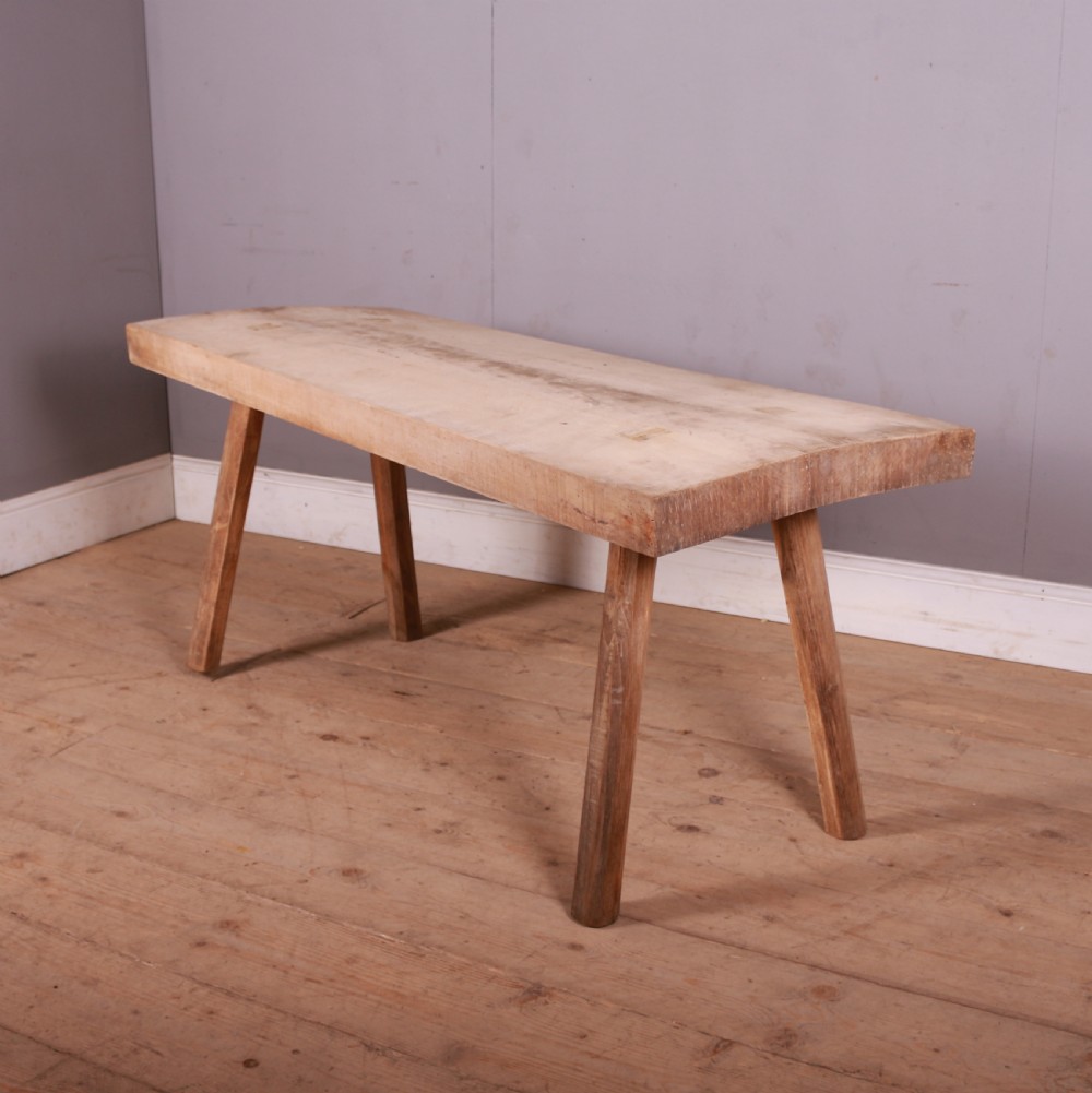 A rustic French trestle table crafted from scrubbed sycamore and elm featuring a thick rectangular top supported by splayed timber legs.