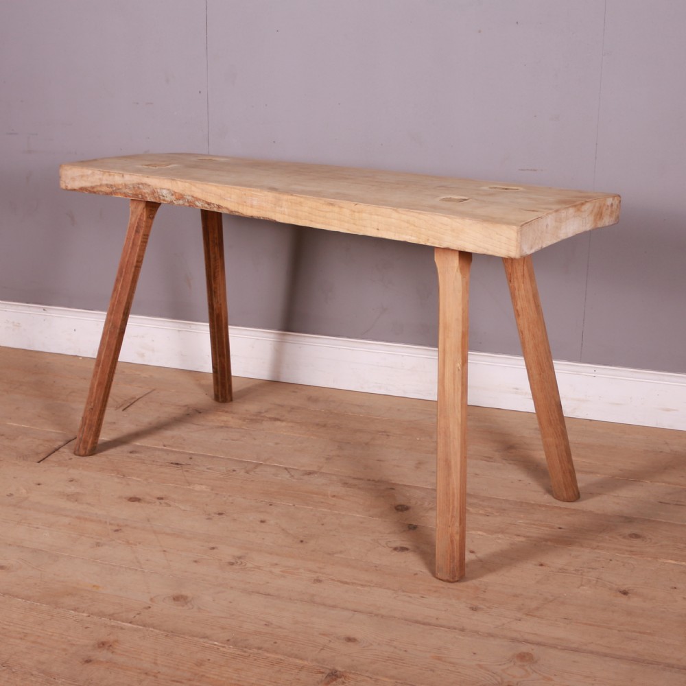 A rustic rectangular timber trestle table crafted from pale sycamore and elm with splayed wooden legs and exposed joinery.
